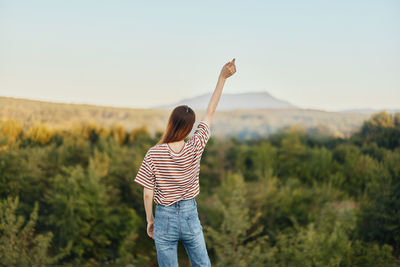 Rear view of woman standing on field against sky