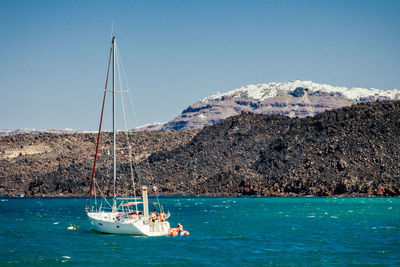 Boat on turquoise sea against mountains