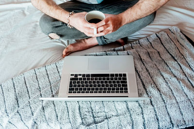 Man drinking coffee while working from bed in madrid.spain.