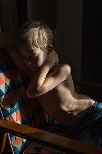 Shirtless boy sitting on sofa