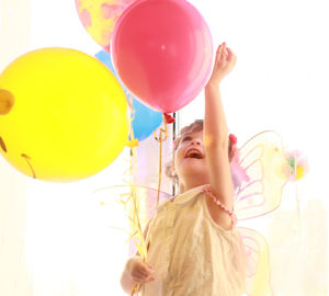 Low angle view cute girl with balloons wearing angel costume