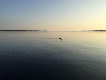 Scenic view of lake against clear sky during sunset