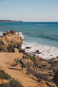 High angle view of mid adult woman standing on cliff against sea