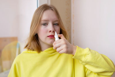 Portrait of young woman applying lipstick