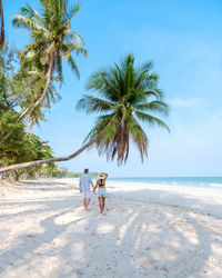 Rear view of woman walking on beach against sky