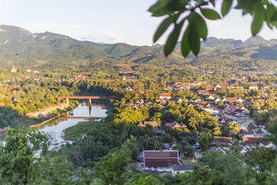 Scenic view of townscape by tree mountain against sky