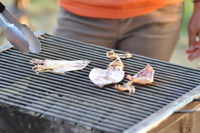 Midsection of person preparing food on barbecue grill