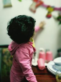 Side view of girl touching wall at home