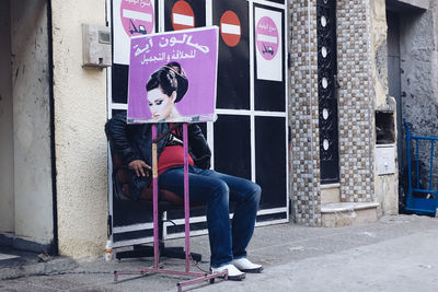 Man sitting on chair against wall