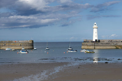 Sailboats on sea by buildings against sky