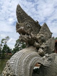 Low angle view of buddha statue against cloudy sky