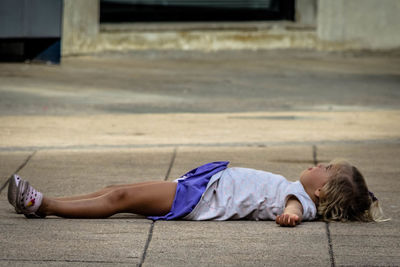 Boy lying on street in city