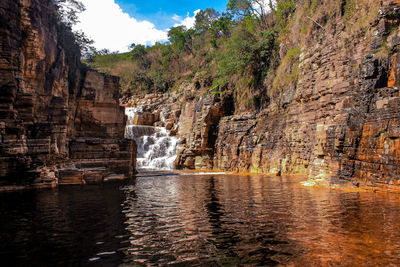 Water flowing through rocks against sky