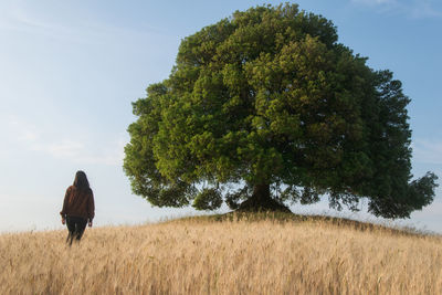 Rear view of woman on field against sky