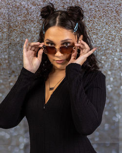 Young woman wearing sunglasses while standing against plants