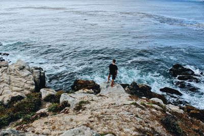 High angle view of man standing on rock by sea