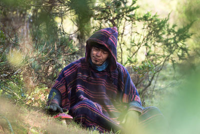Colombian native american man in traditional clothing sitting in forest