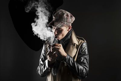 Young man wearing jacket smoking pipe
