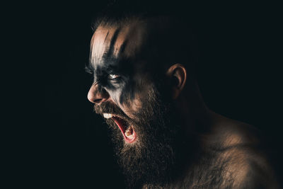 Portrait of a viking warrior with black war paint, screaming with rage and anger