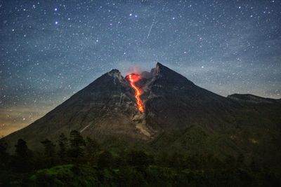 Smoke emitting from volcanic mountain against sky at night