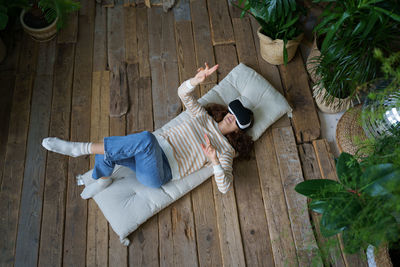 Young astonished woman in casual clothes feeling excited while using 360 vr headset at home