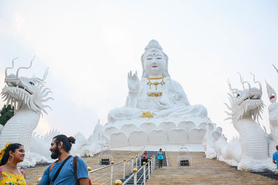 Group of people at temple against sky