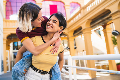 Laughing lesbian couple walking against building