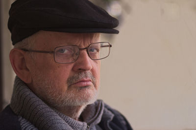 Close-up portrait of senior man wearing eyeglasses and cap