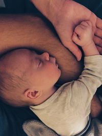 Midsection of father with sleeping son bed at home