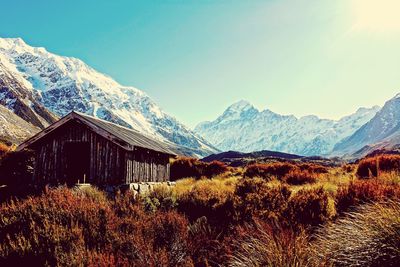 House on field against snowcapped mountain