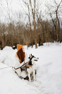 Young woman with dog on snow covered field