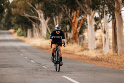 Full length of woman cycling on road
