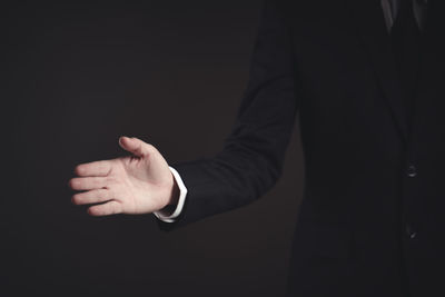 Midsection of person standing against black background