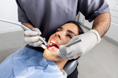 Close up view of the hands of a dentist with gloves cleaning the teeth of a patient in a clinic