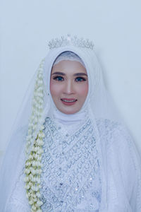 Portrait of smiling young woman in warm clothing standing against white background