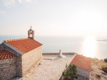 Rear view of lighthouse on building by sea against sky