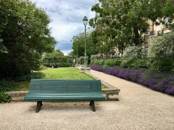 Empty bench in park against sky