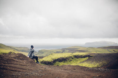 Side view of woman sitting on top of mountain