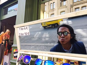 Reflection of man wearing sunglasses while puckering lips on mirror
