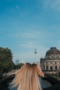 Rear view of woman in city against sky