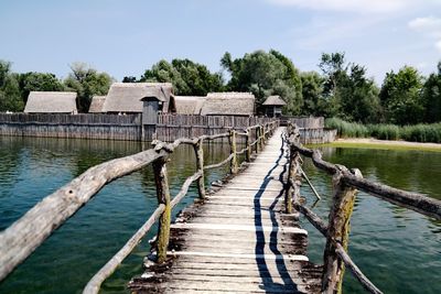 Wooden posts in lake against sky