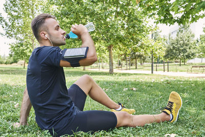 Man drinking sports drink after training. he is in an outdoor park.