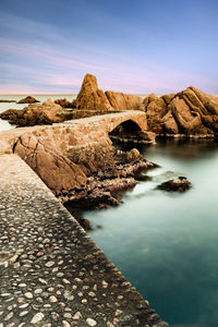 Scenic view of rock formations by sea against sky