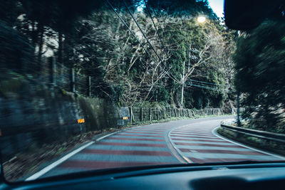 Road amidst trees seen through car windshield