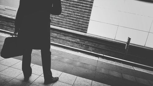 Low section of man with bag standing on railroad station platform