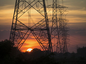 Low angle view of silhouette electricity pylon against sky during sunset