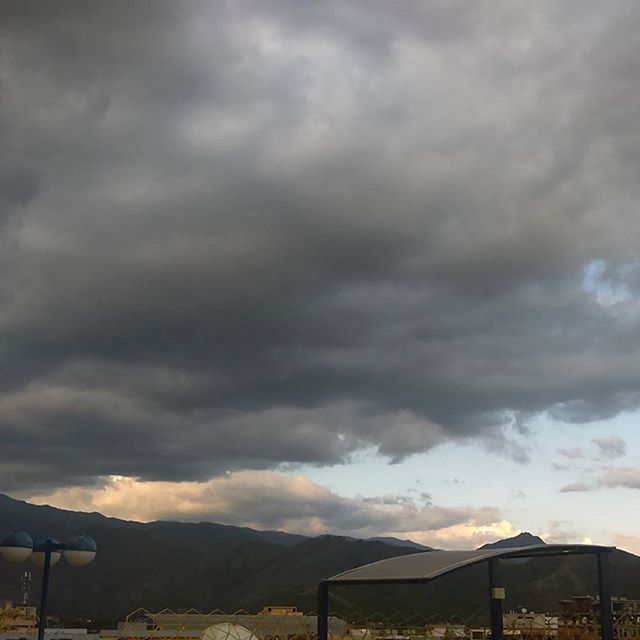 sky, cloud - sky, cloudy, mountain, weather, overcast, scenics, beauty in nature, mountain range, cloud, nature, tranquil scene, tranquility, cloudscape, storm cloud, landscape, built structure, dramatic sky, low angle view, outdoors