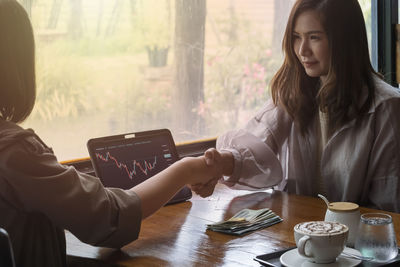 Young woman using mobile phone while sitting on table