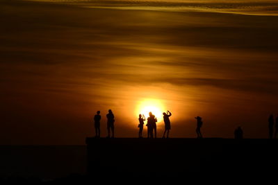 Silhouette people on beach during sunset