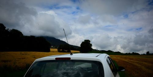 Car on road amidst field against sky
